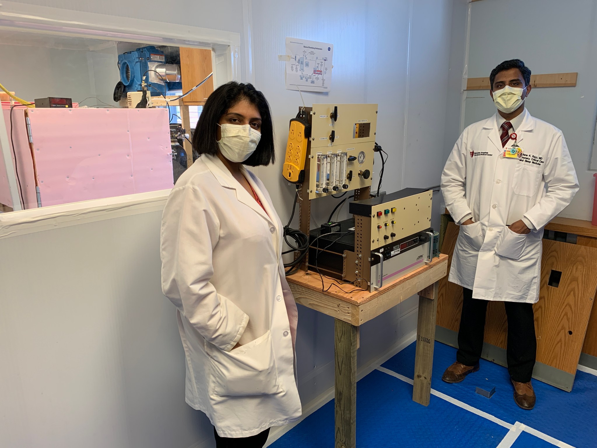 Female and male doctor, wearing masks, standing on either side of the device.