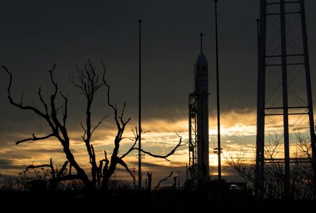 The Antares rocket stands on the pad, silhouetted against an heavily overcast sky.