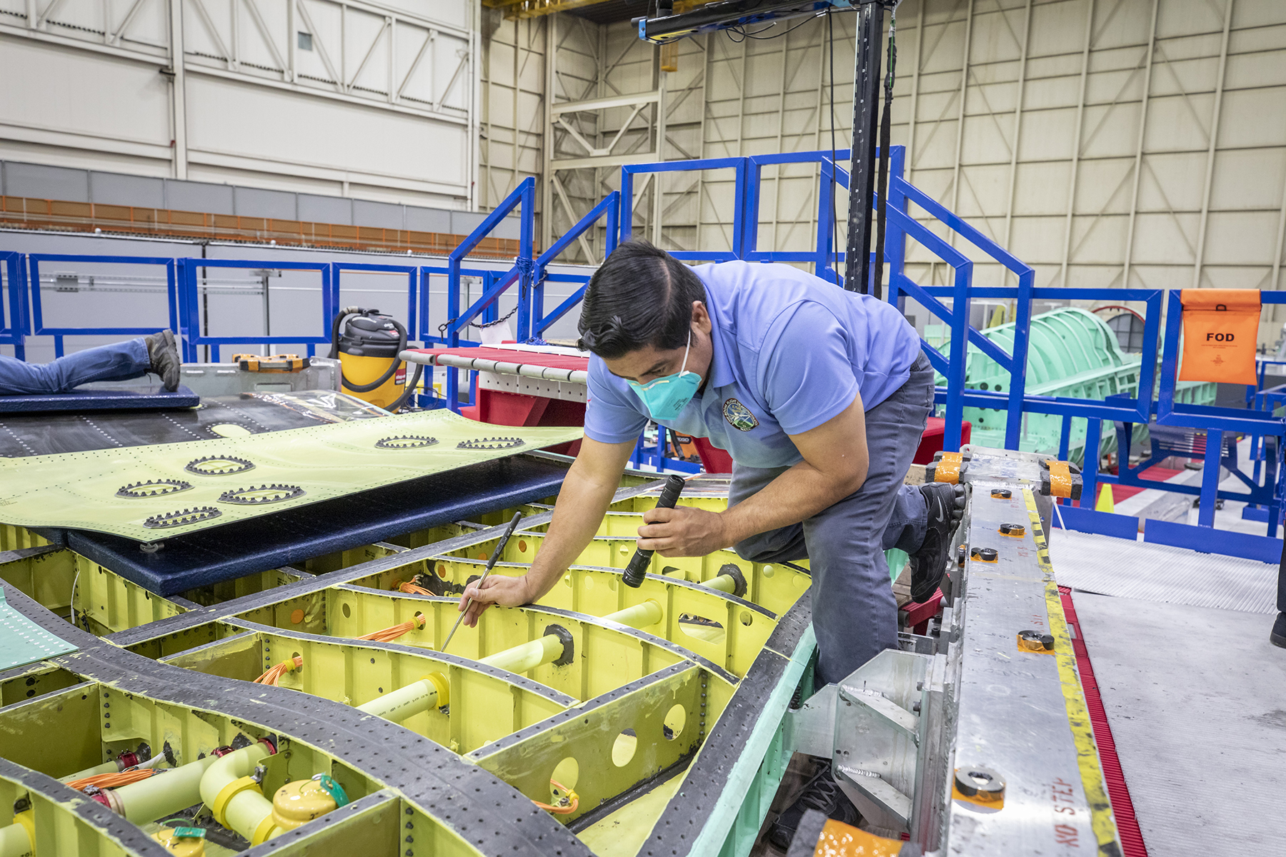 A techniian performing an inspection of the interior bay of the wing on NASA's X-59.