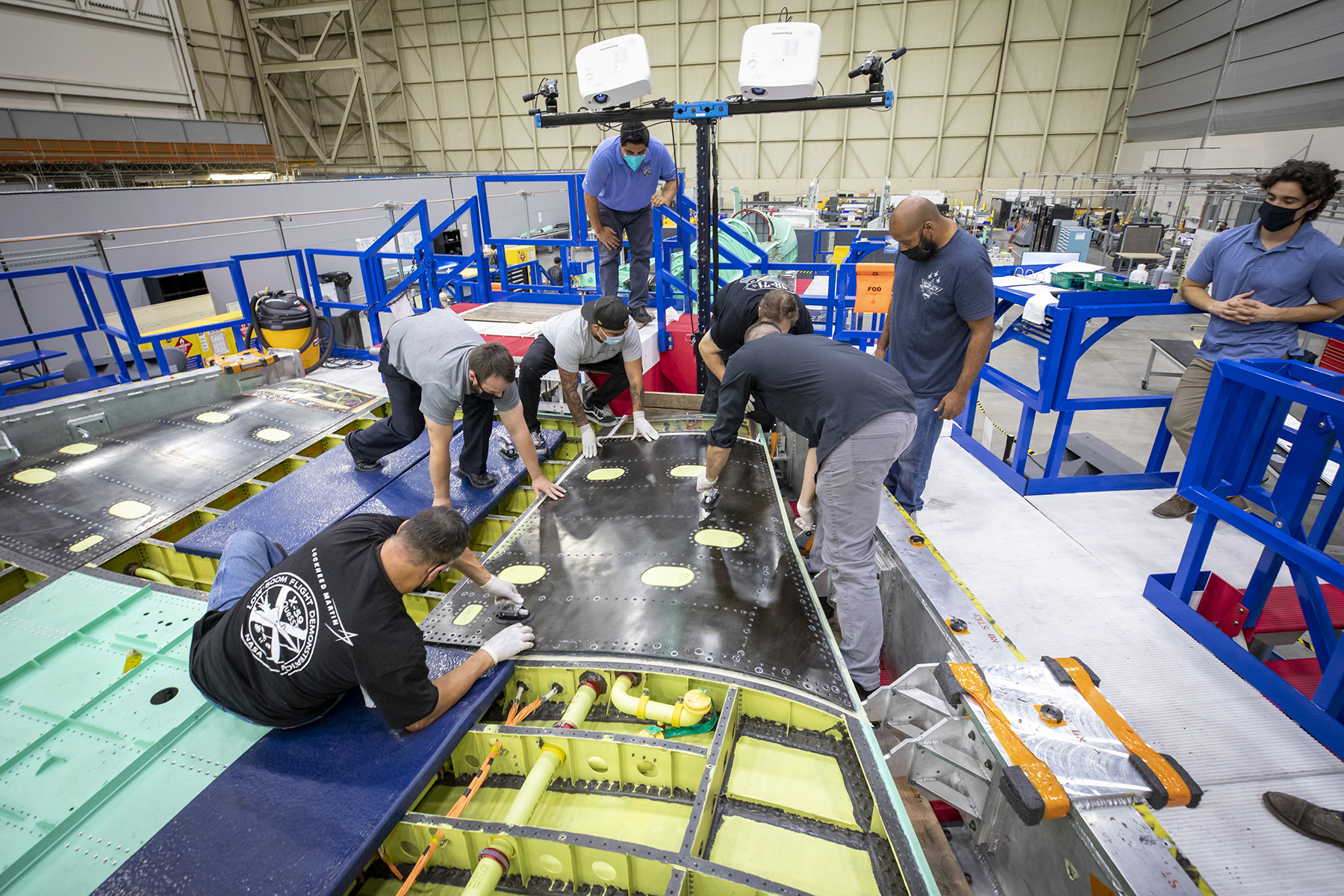 A panel of the dark-colored skin of the wing of NASA's X-59 airplane is laid in place over the wing's interior framework.