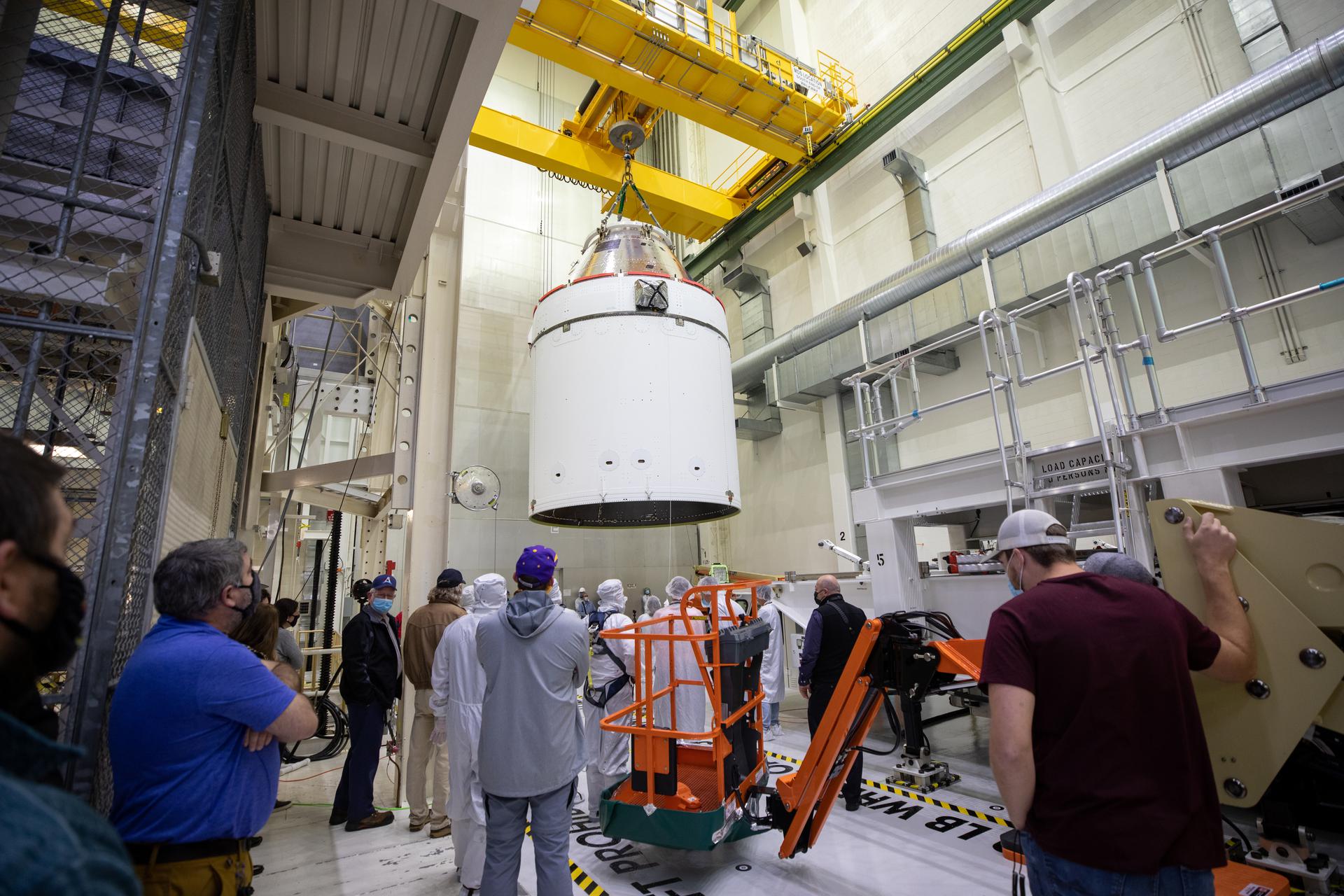 Orion processing team members view Orion on Jan. 14, as it is moved by crane to its transport pallet at Kennedy Space Center.