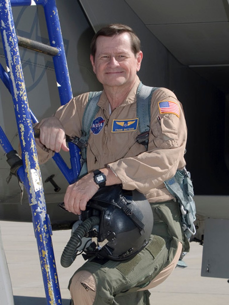 Man in flight suit posed on a ladder.