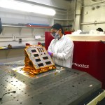 Female researcher in lab inspecting an experiment set up on a vibration table.