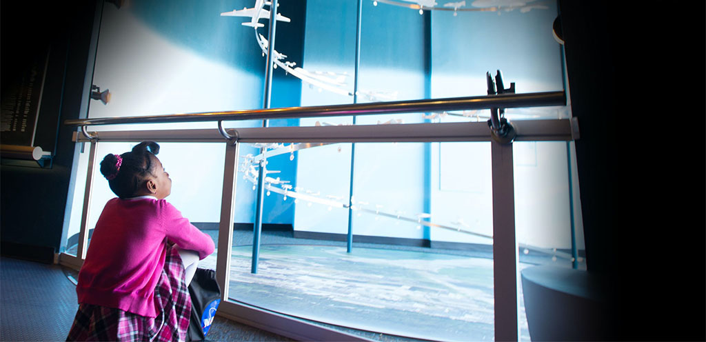 Young girl observing a display of aeronautics models.