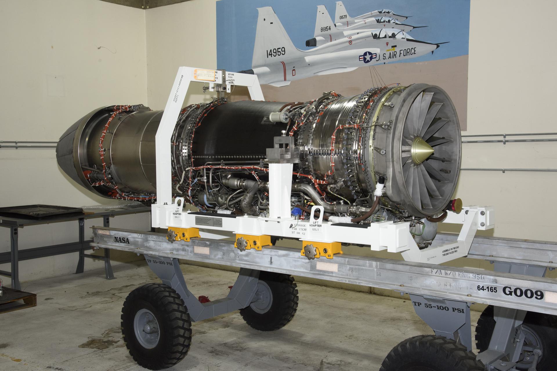 A large aircraft engine sits on a transport dolly in a storage facility.