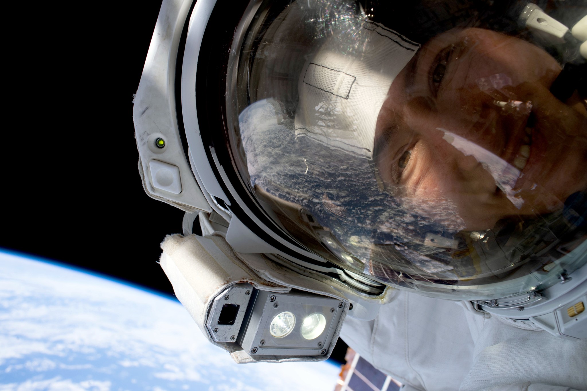 NASA astronaut Christina Koch's face seen closeup during a spacewalk with Earth in the backdrop