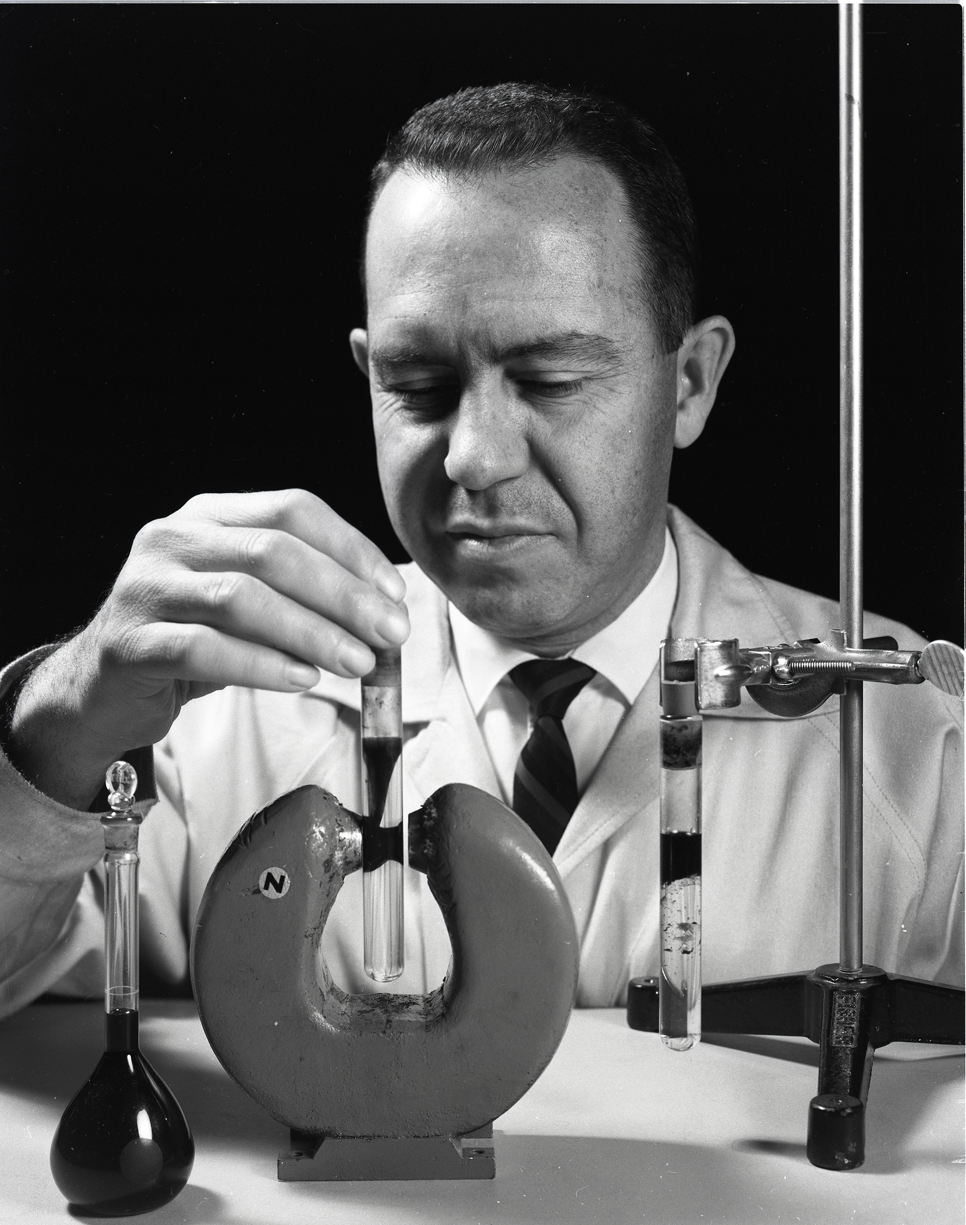 Researcher holds a test tube of liquid near a large magnet.