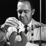 Researcher holds a test tube of liquid near a large magnet.