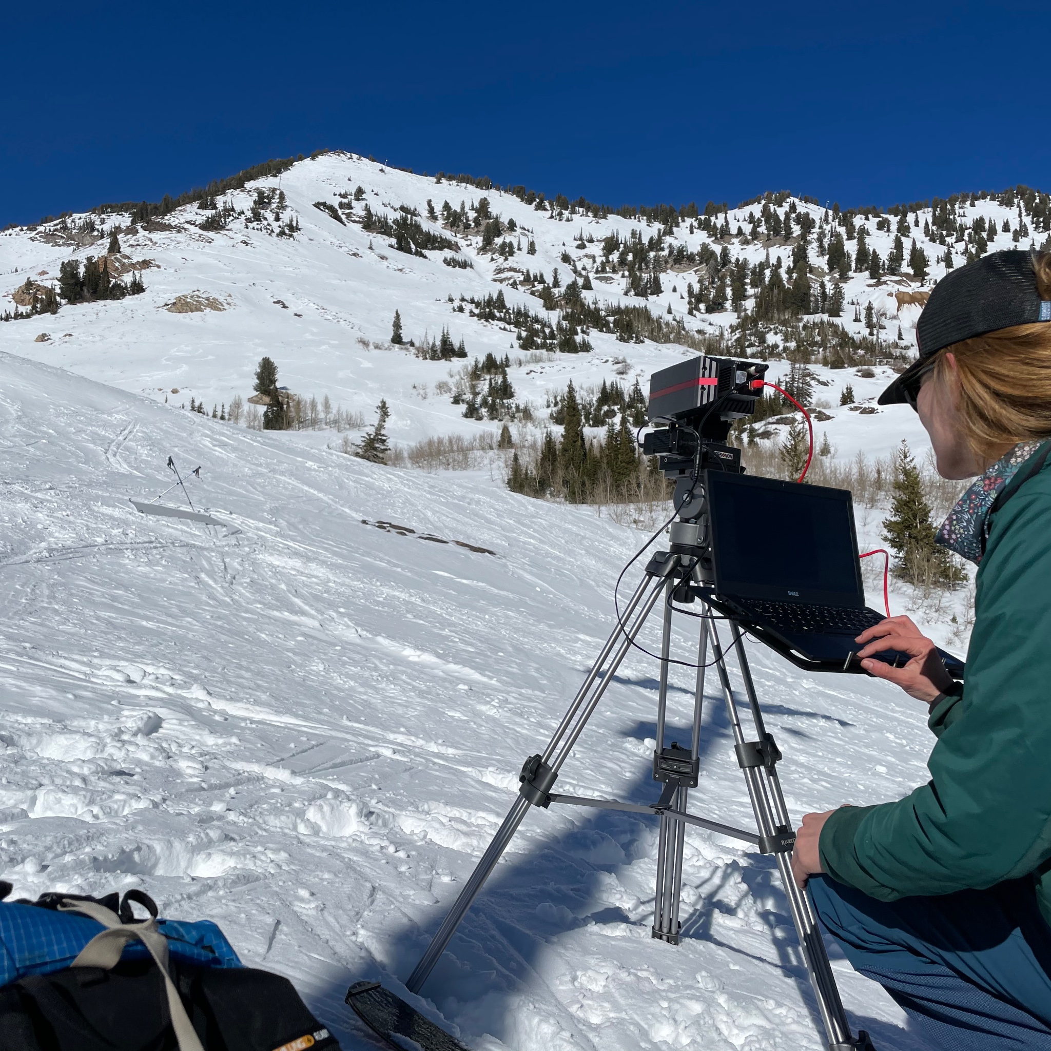 Snow scientist using a tripod-mounted instrument to study snowy landscape