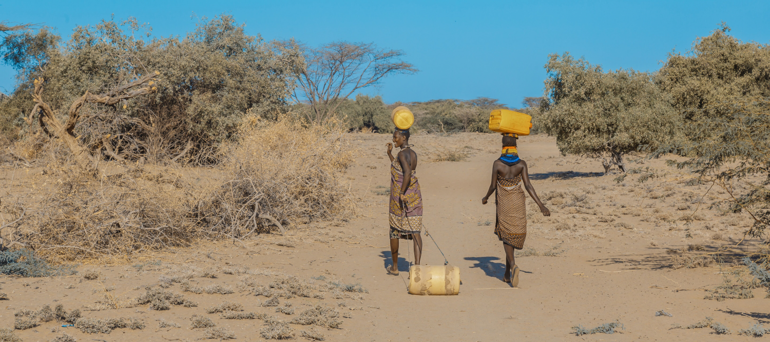 Photo of women in African dress carrying water