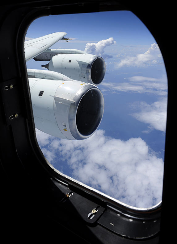 Looking out of an airplane window at the wing and engine. Blue skies in teh background.