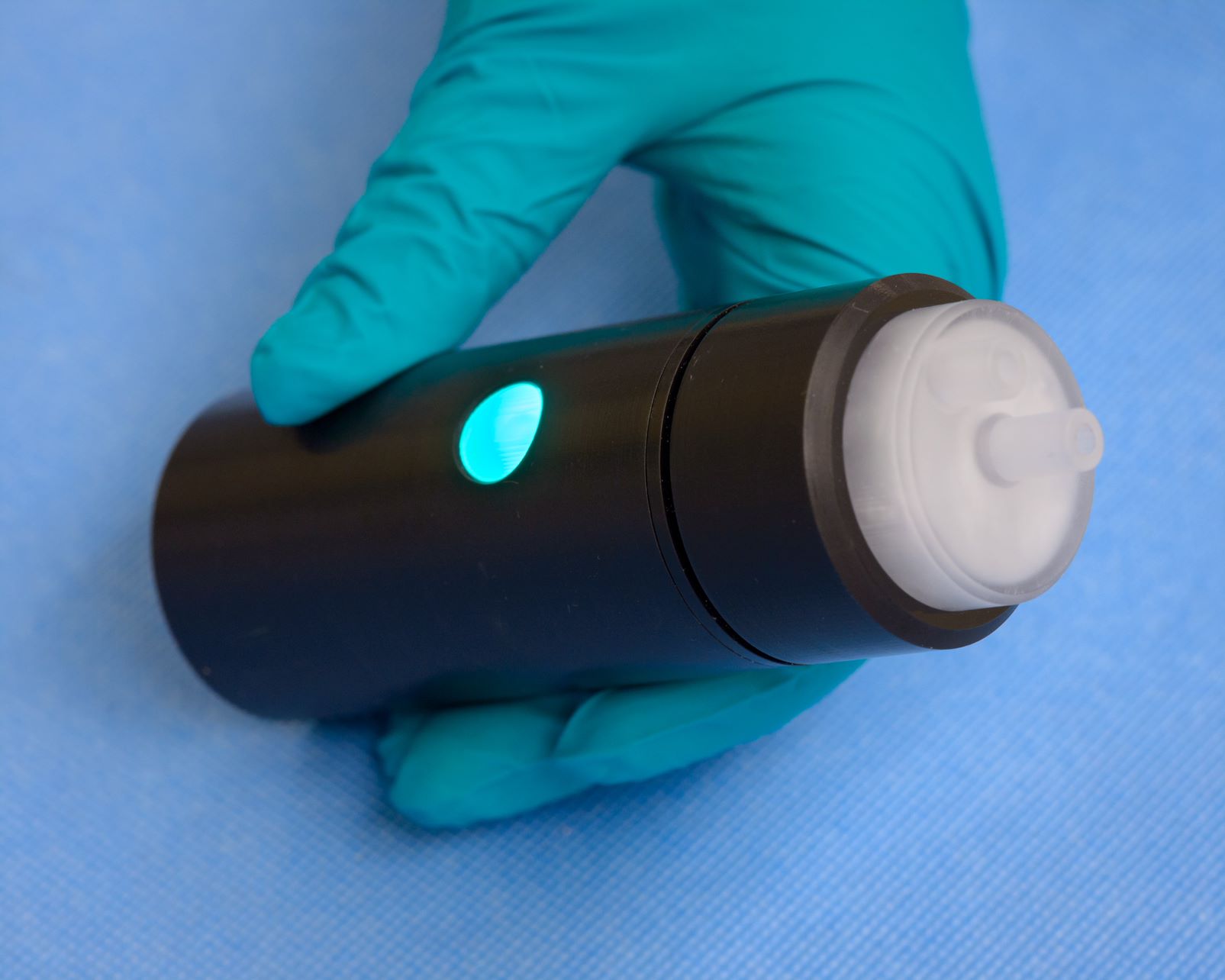 A bottle-like device, with a blue light at the center and a nozzle at the top.