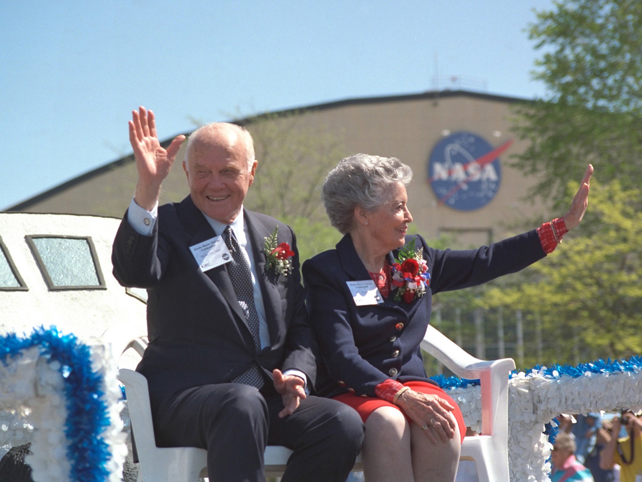 John and Annie Glenn are seated on a parade float at NASA Glenn