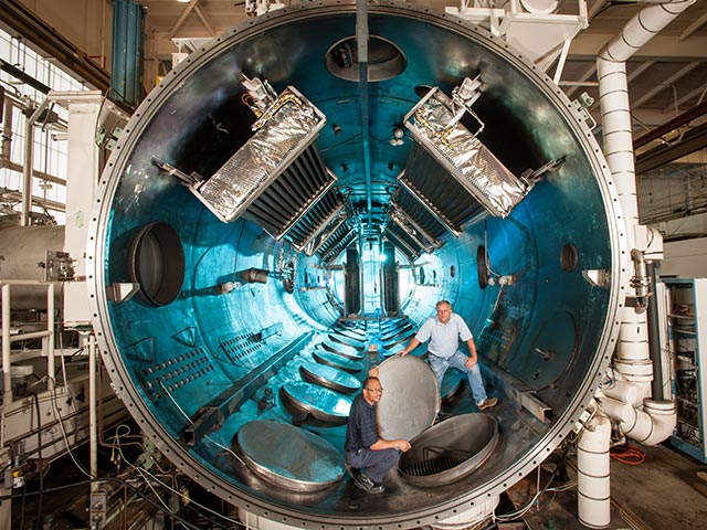 View of the cylindirical VF-5 thermal vacuum facility chamber with two men inside