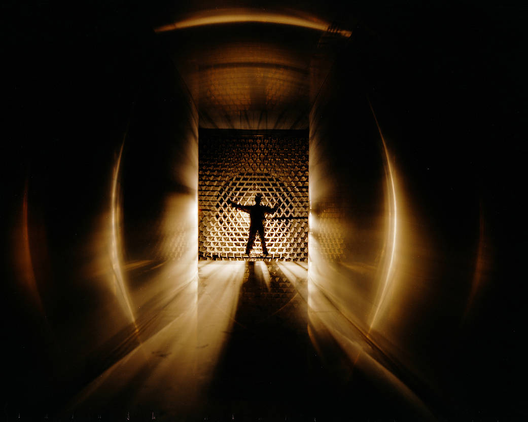 Black and gold image showing a silhouette of a man inside a wind tunnel.