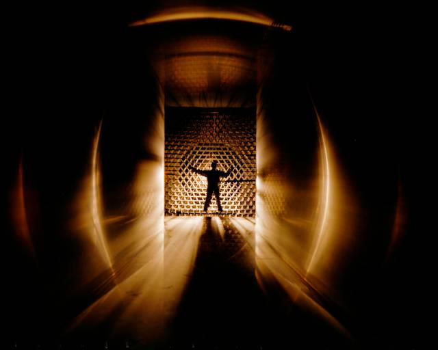 Black and gold image showing a silhouette of a man inside a wind tunnel.