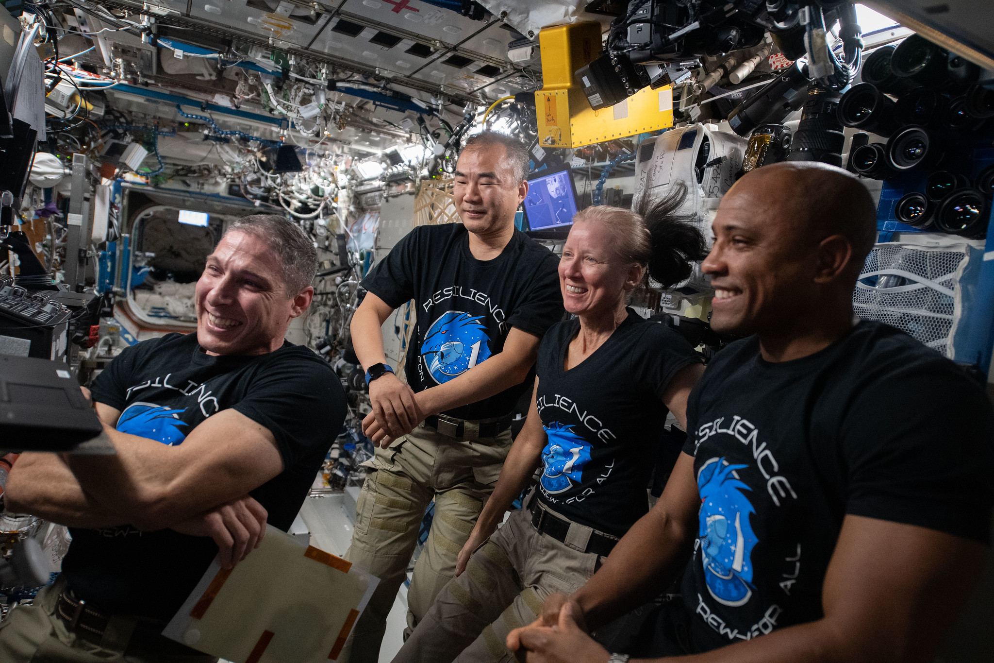 Four Expedition 64 flight engineers, who also are the NASA’s SpaceX Crew-1 astronauts, gather around a laptop computer to join a video conference on Feb. 7, 2021.
