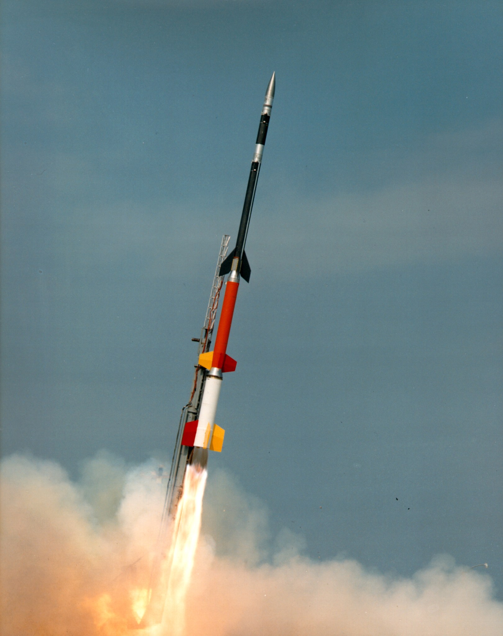 A sounding rocket launching from a launch pad with a plume of smoke forming underneath.