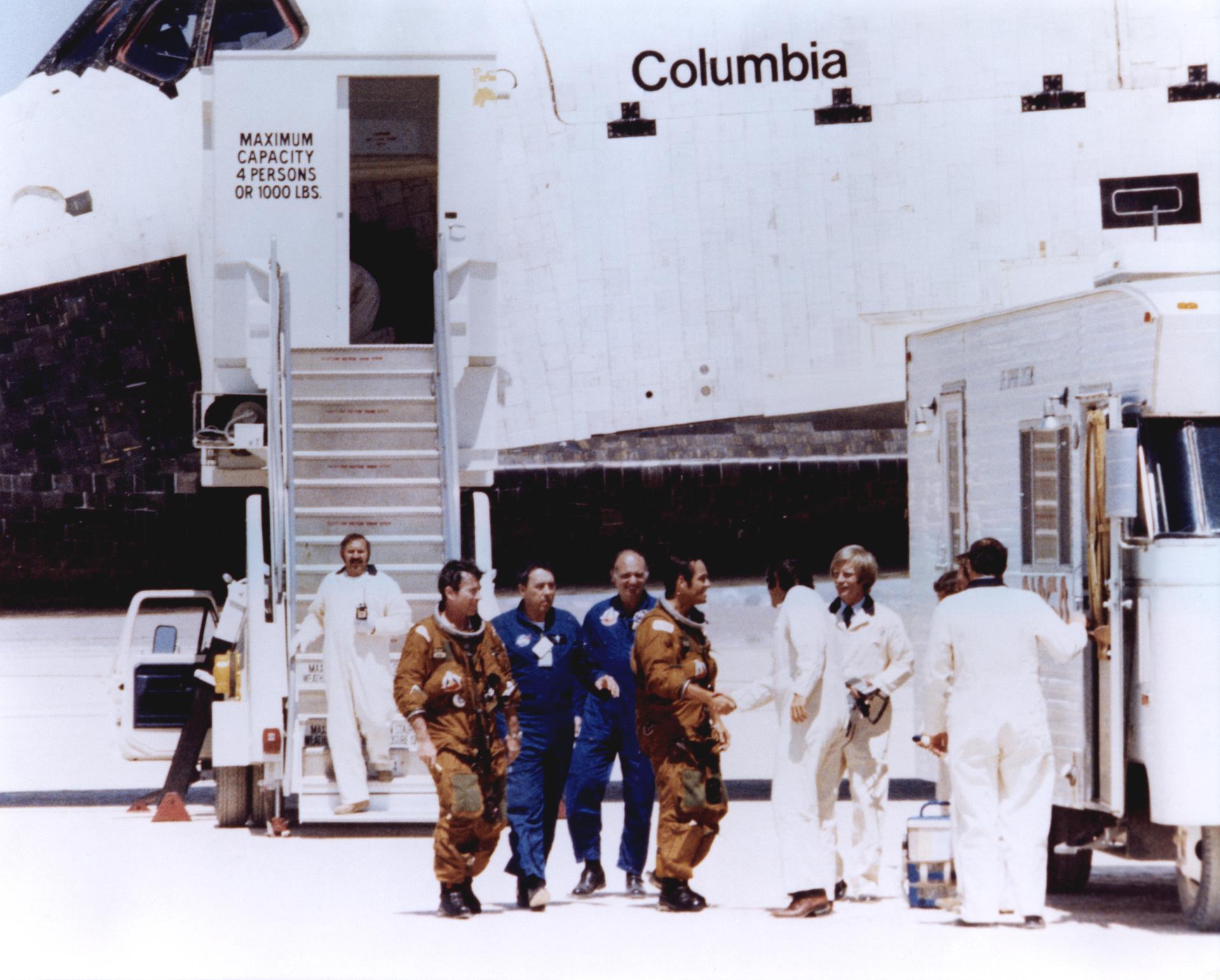 NASA Space Shuttle astronauts John Young and Robert Crippen (in tan space suits) are greeted by members of the ground crew after
