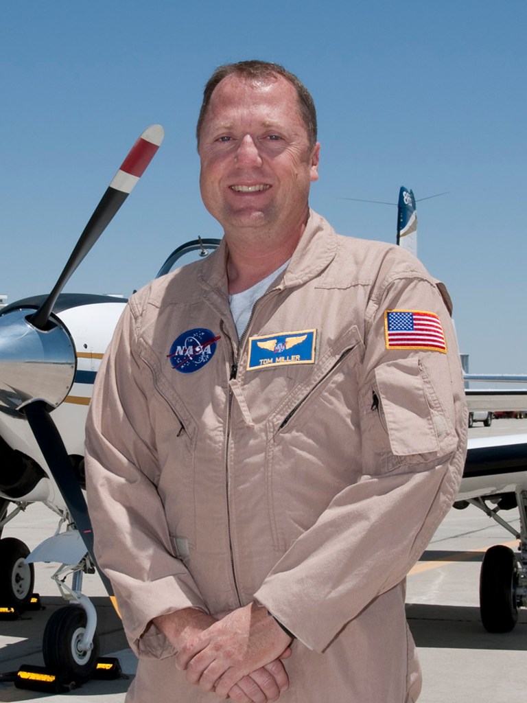 Man standing in front of an aircraft, smiling.