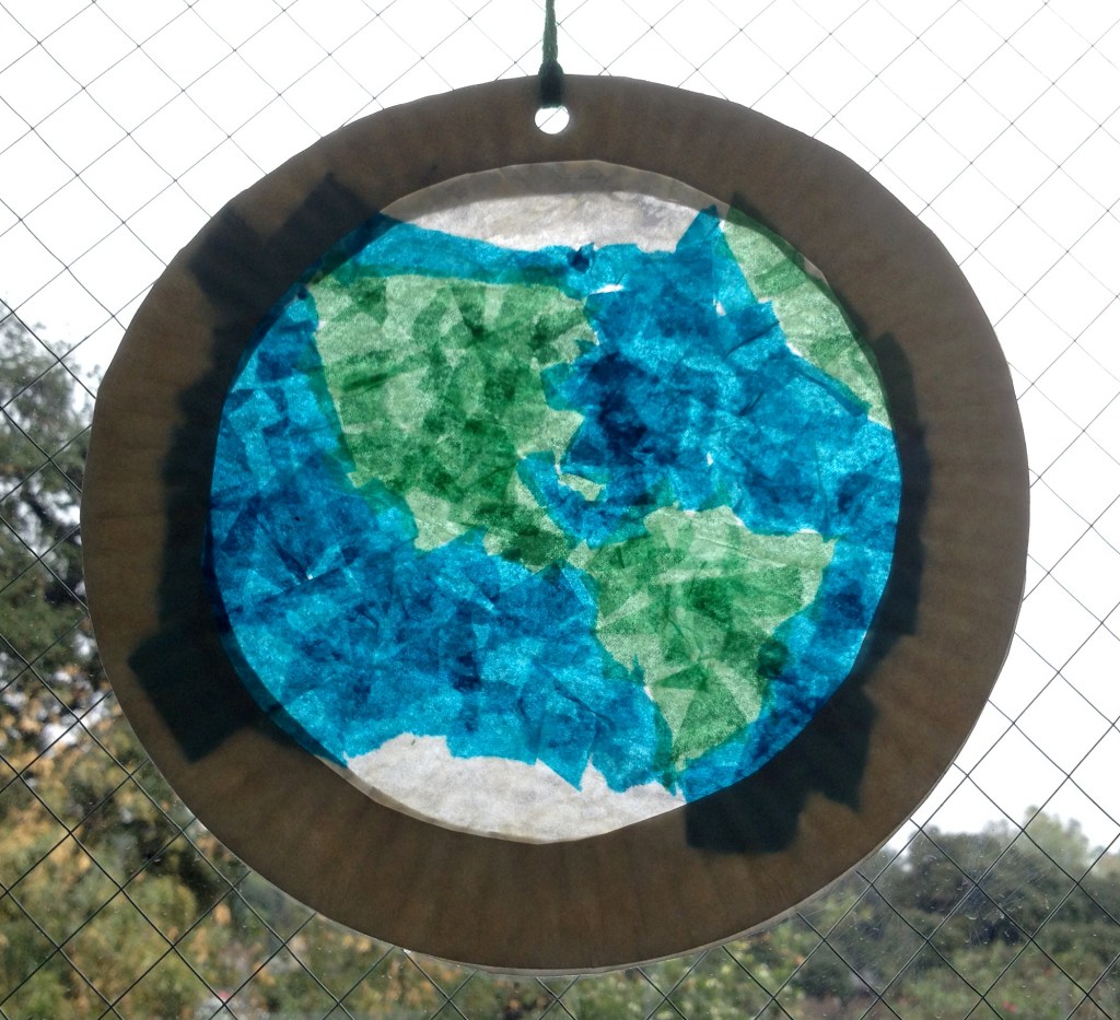 A colorful craft made from a paper plate and tissue paper to look like a stained glass Earth