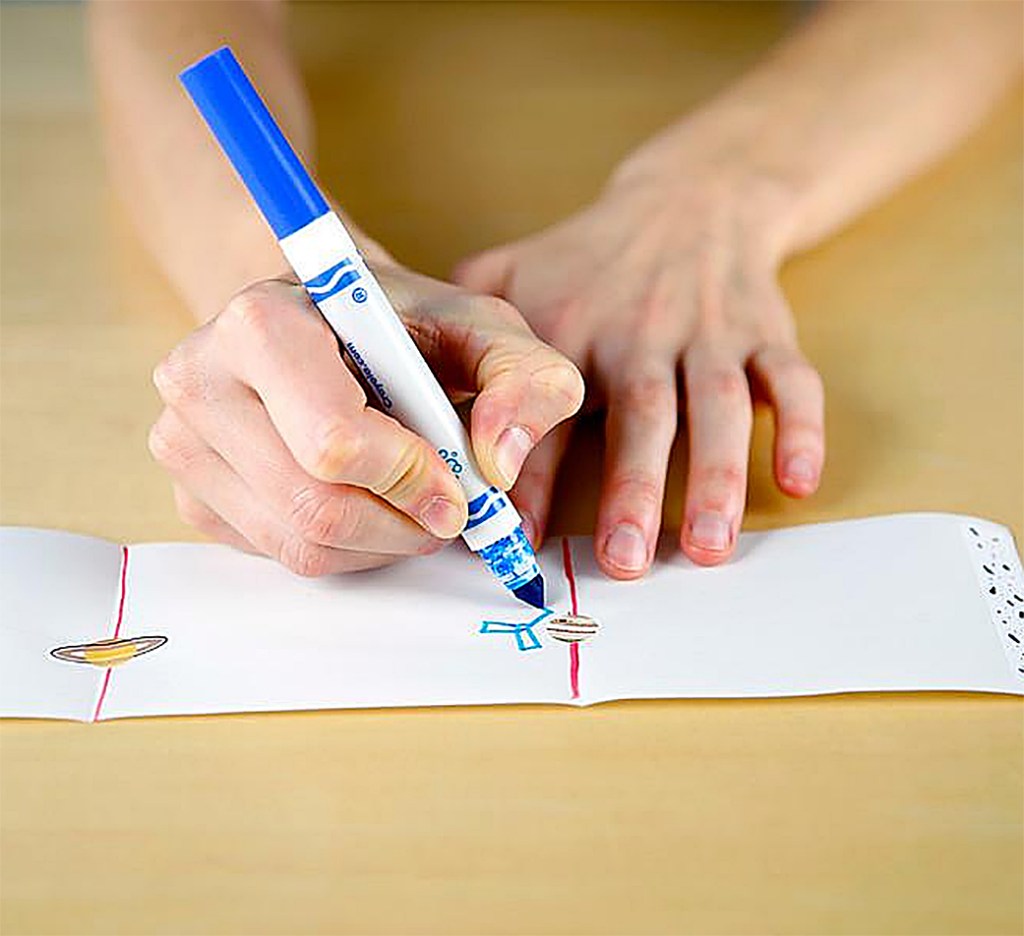 Hands shown drawing planets on a strip of paper
