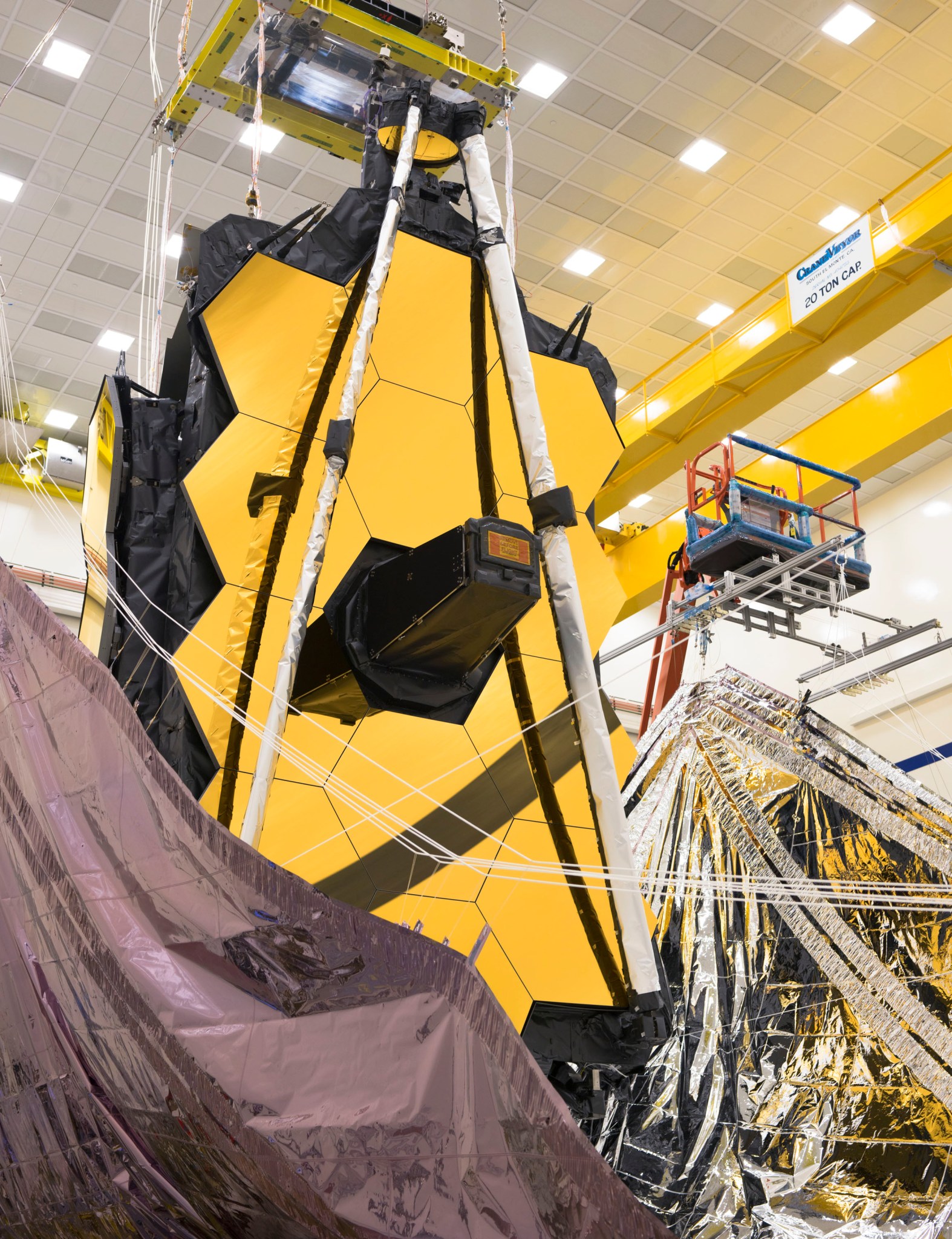 The Webb Telescope's sunshield is lifted vertically on both sides in preparation for the folding process.