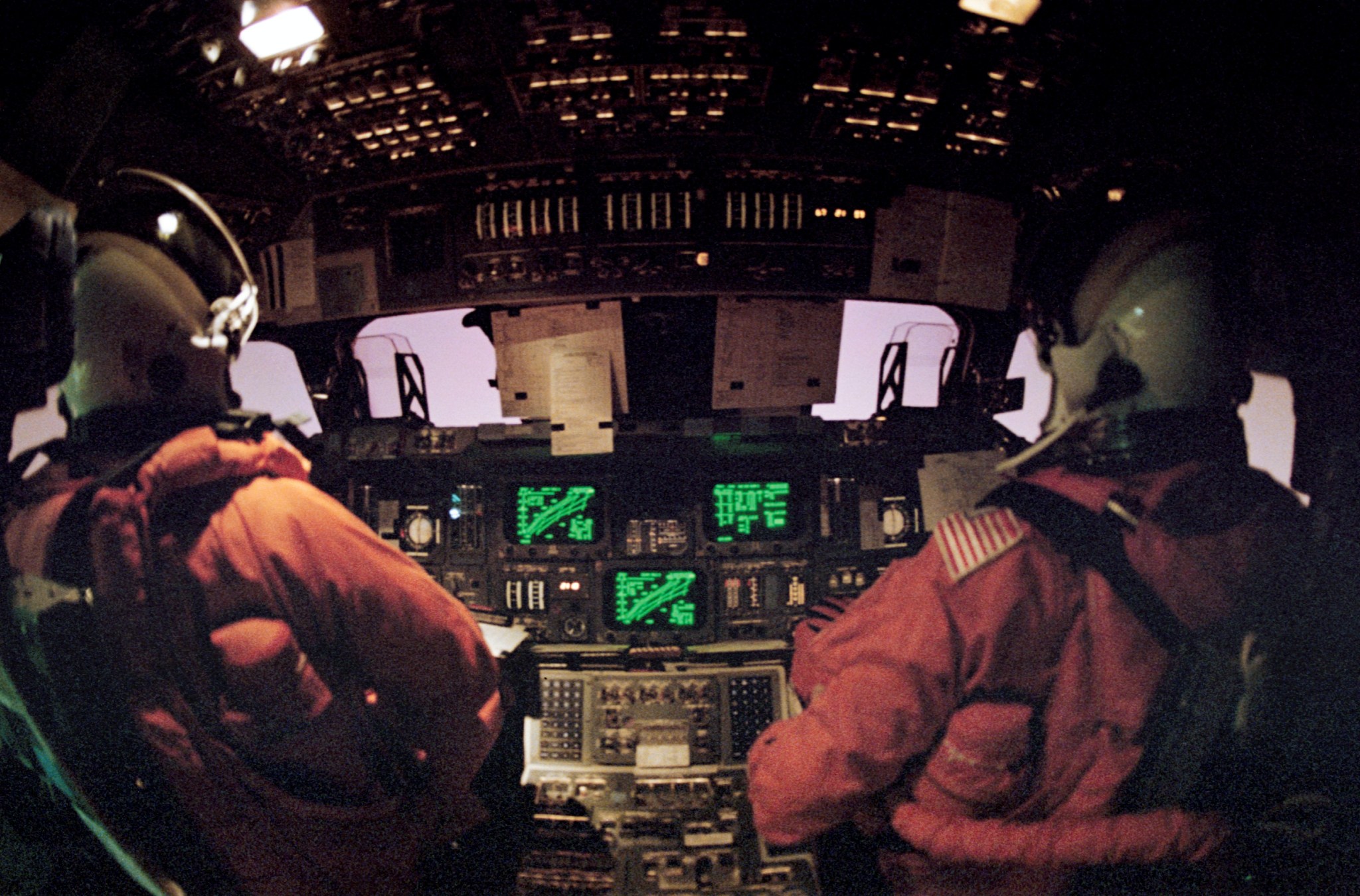 Two people in cabin of space shuttle.