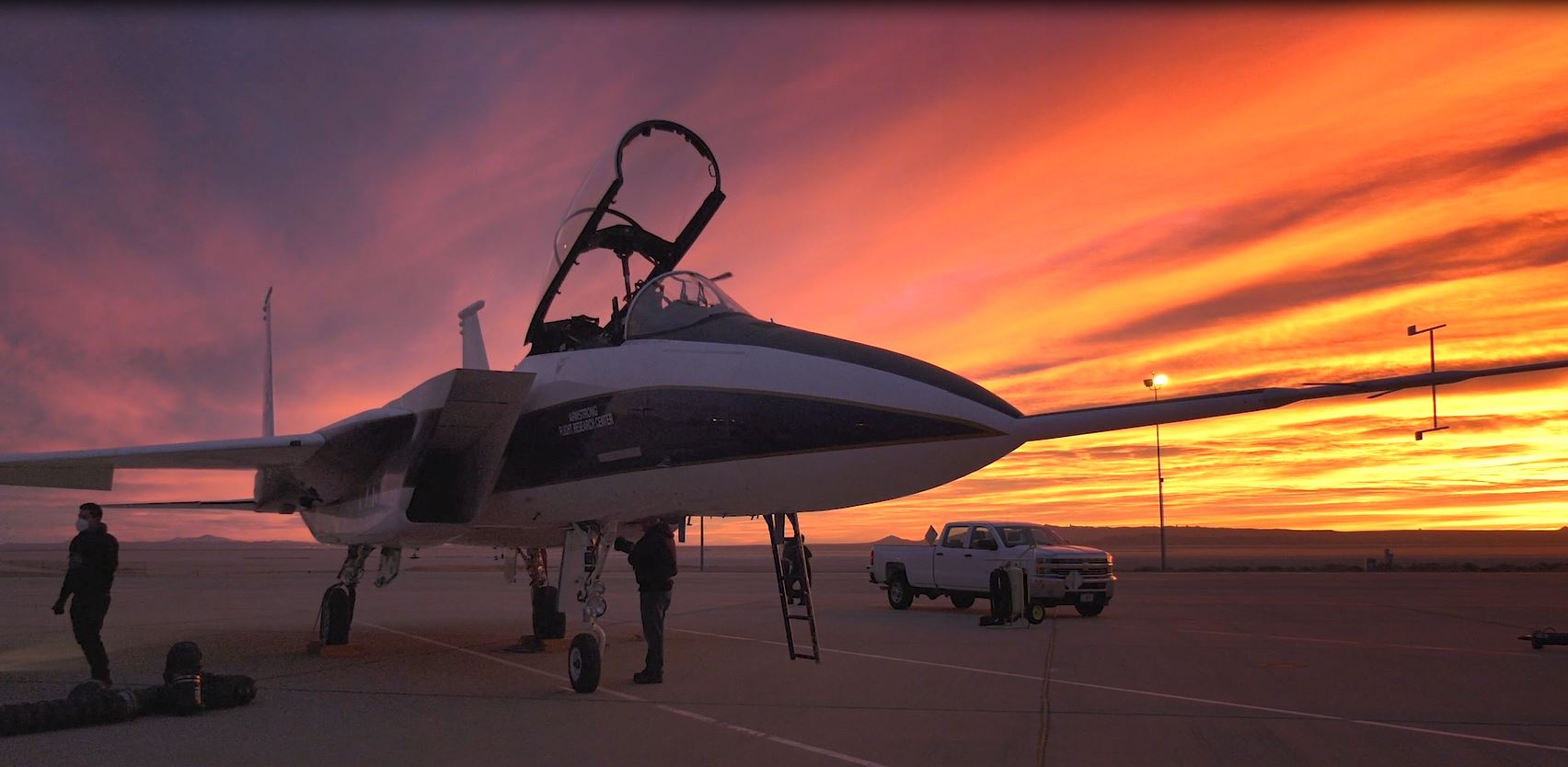 An aircraft on a runway at sunrise.