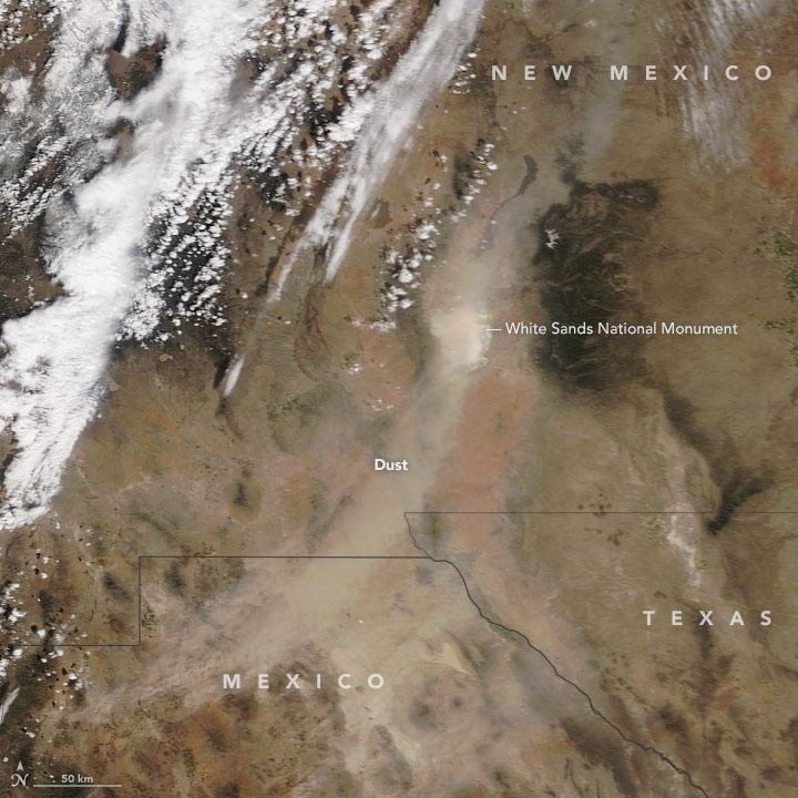 Satellite image of a dust storm over White Sands National Monument. The storm is a curved line of lighter tan smudge against the brown landscape.