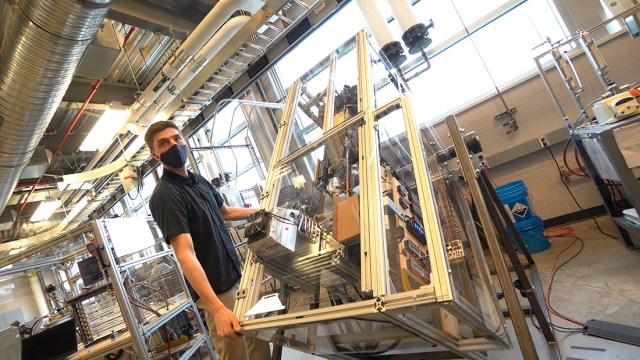 Purdue University Ph.D. student Leon Brendel rotates a highly instrumented fridge experiment designed to work in different orientations