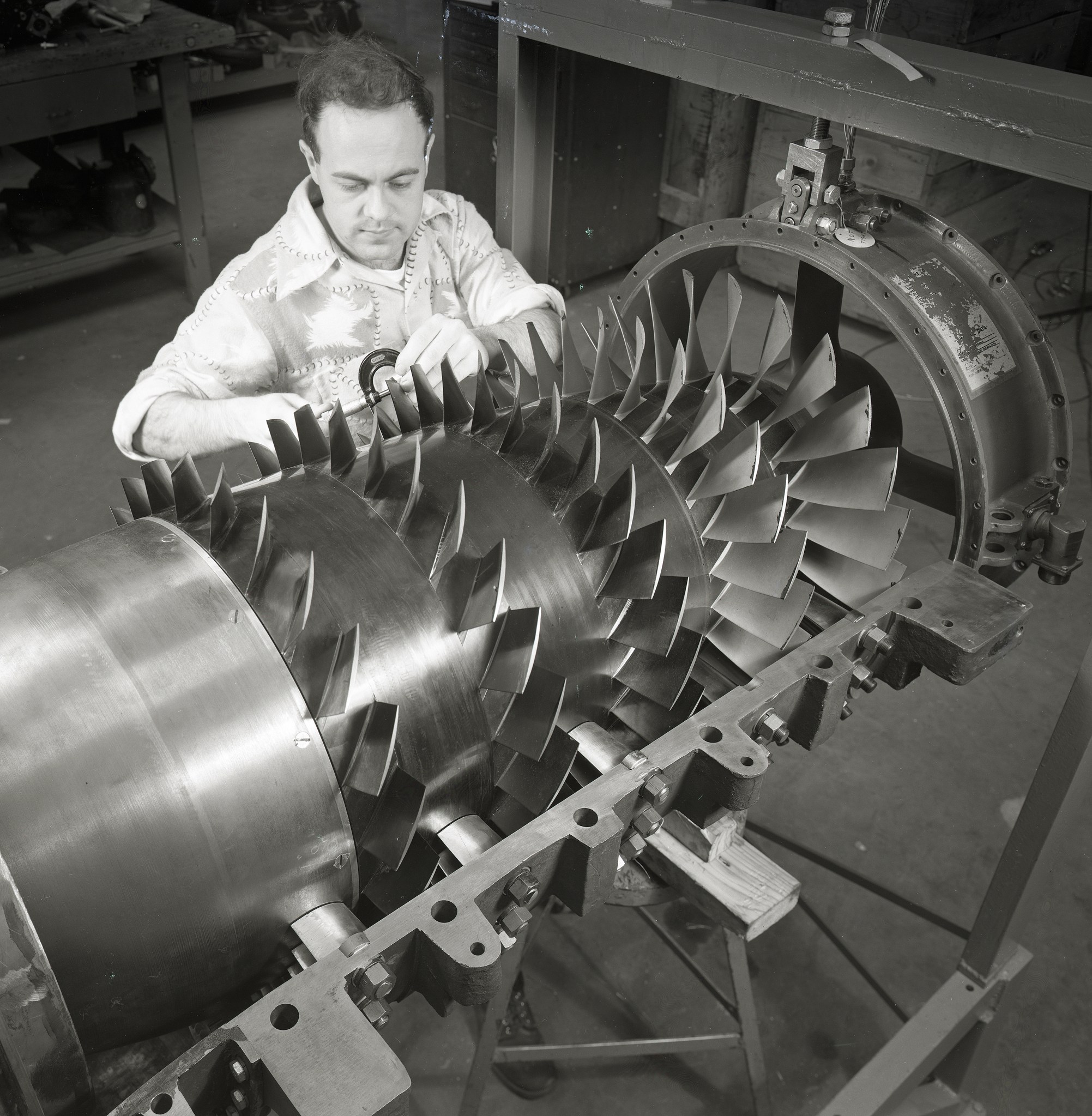 Man examining aircraft engine compressor.