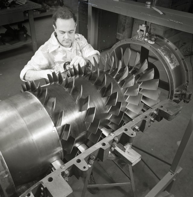 Man examining aircraft engine compressor.