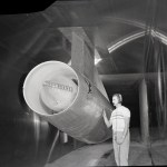 Man standing with large jet engine in wind tunnel test section.
