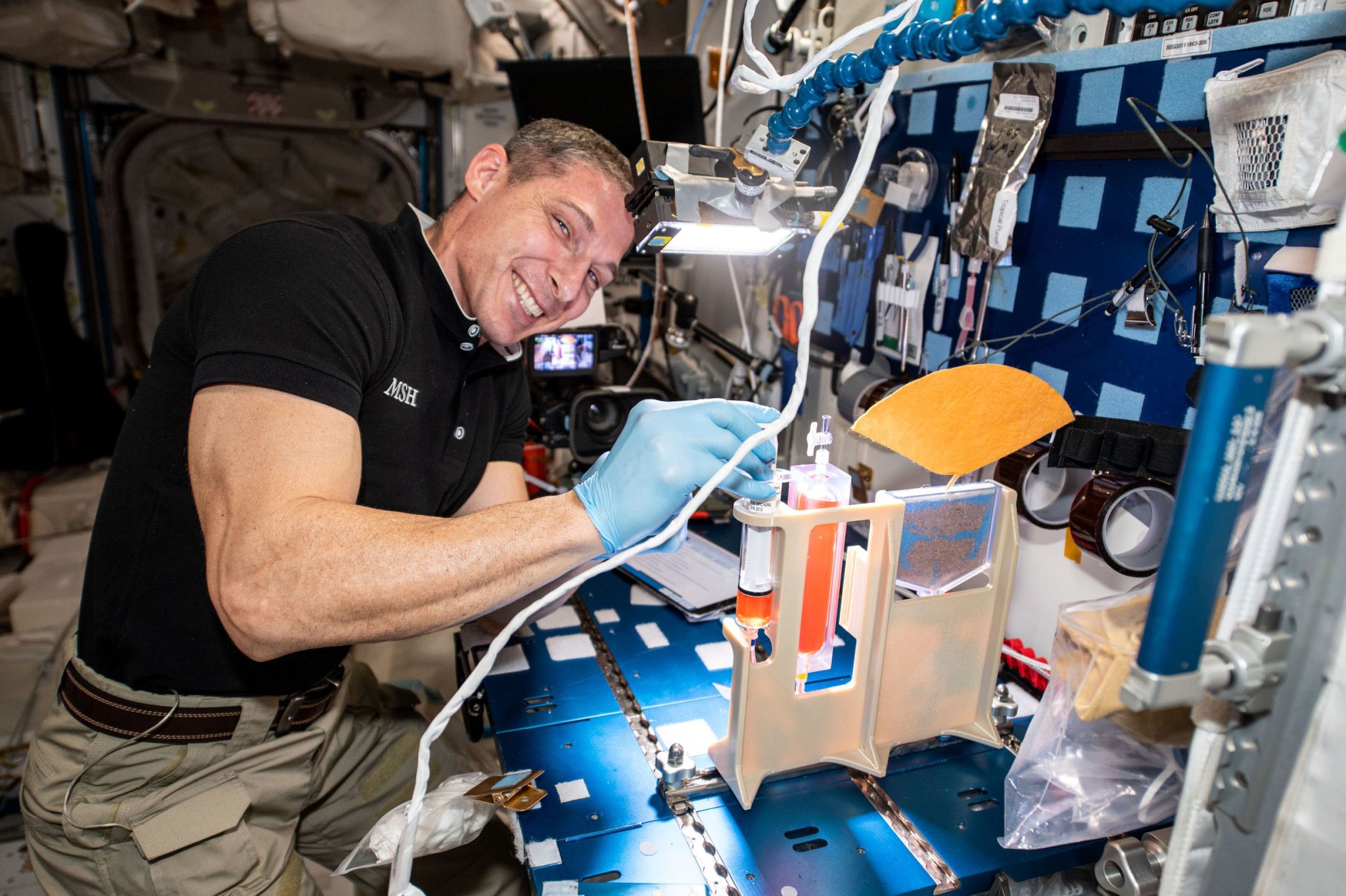 Astronaut smiles at the camera while working on experiment on the space station