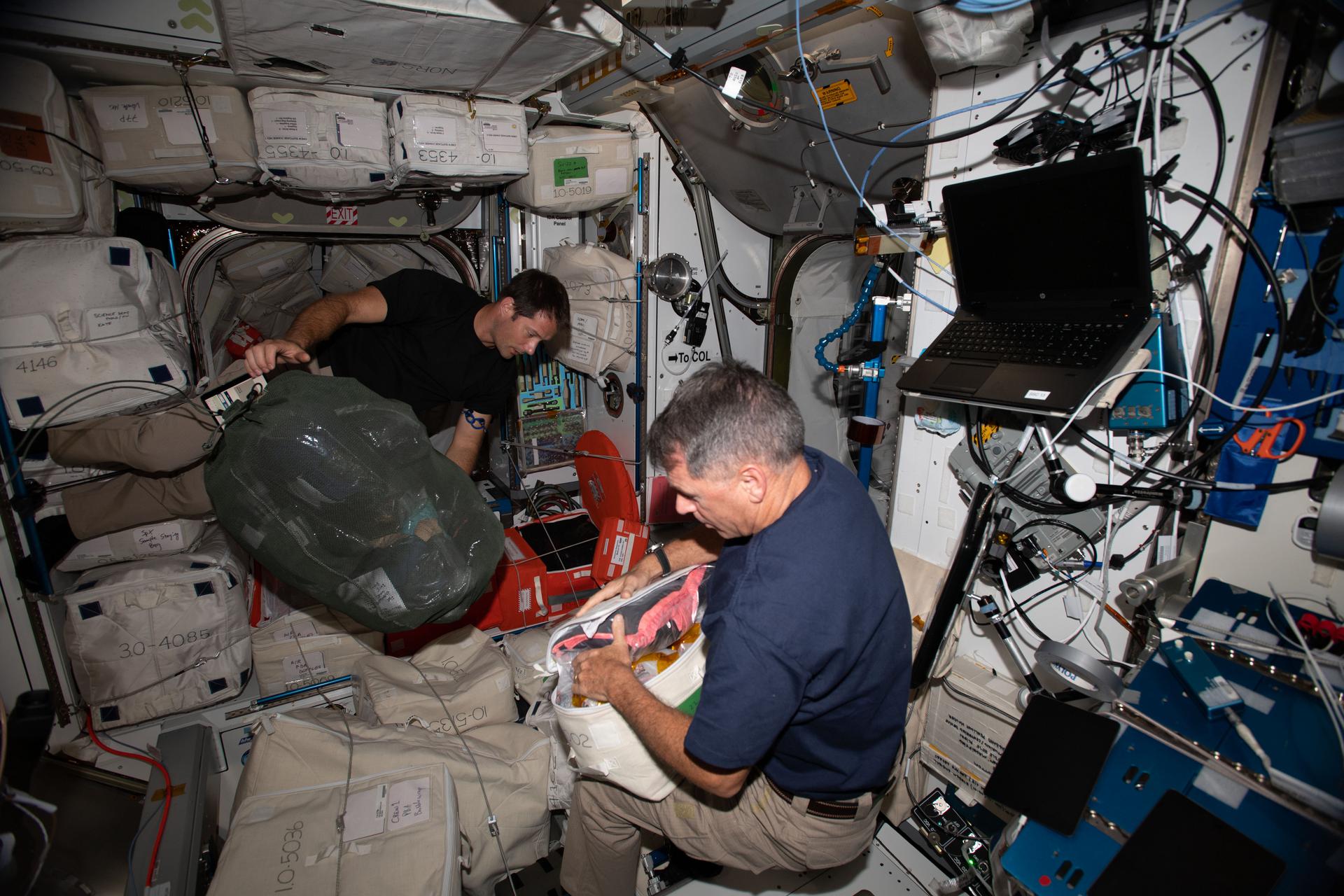 Expedition 65 Flight Engineers (from left) Thomas Pesquet of ESA (European Space Agency) and Shane Kimbrough of NASA gather and prepack cargo to be returned to Earth on the next SpaceX Cargo Dragon mission targeted for launch on June 3, 2021.