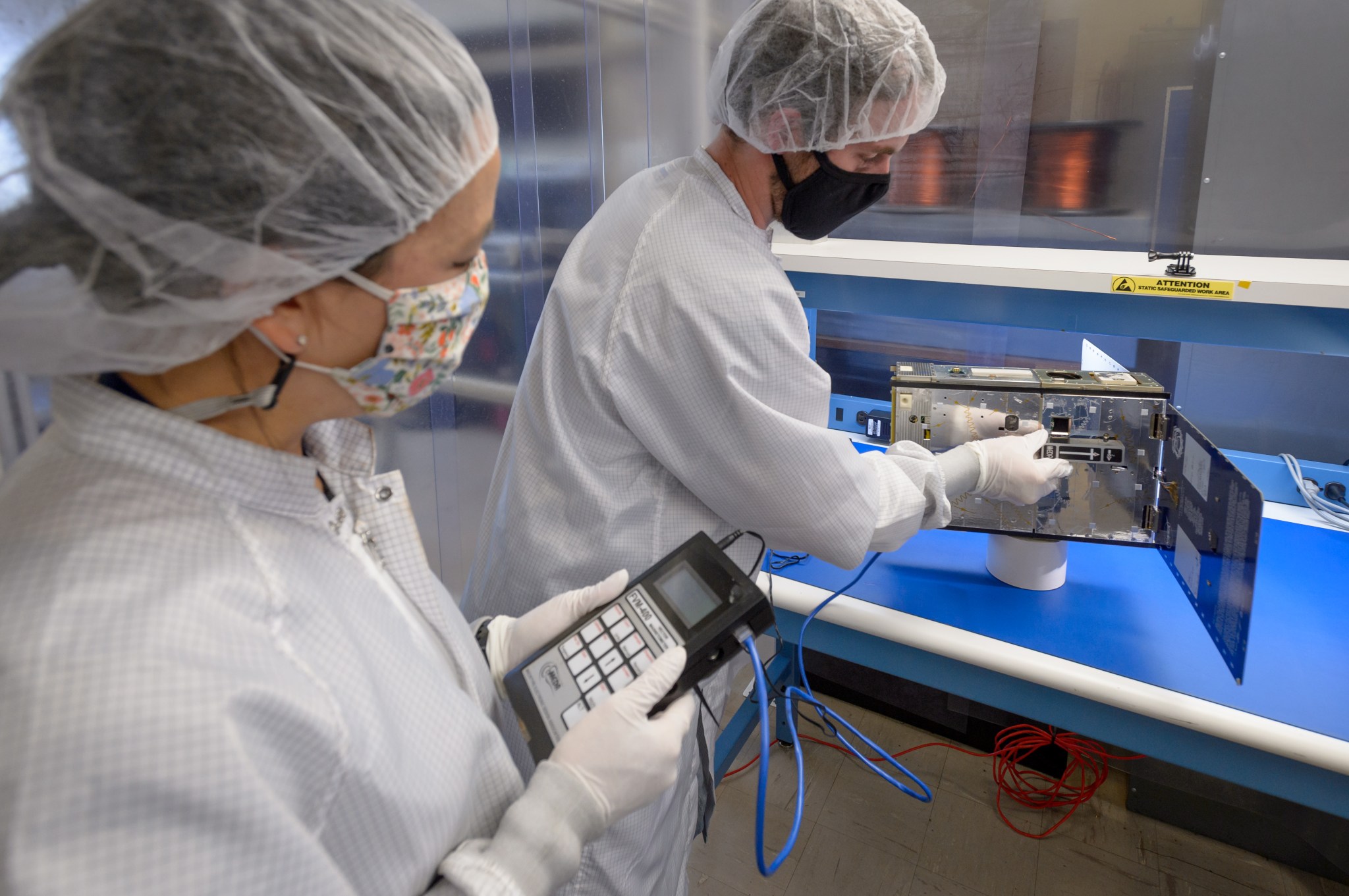 Anh Nguyen, PACE project manager, left, and Connor Nelson, PACE flight software lead, right, perform a magnetometer test on the PACE-1 spacecraft.