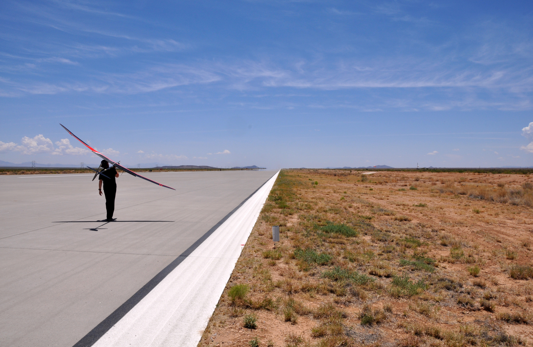 Stratodynamics CEO Gary Pundsack carries the HiDRON glider off the runway at Spaceport America