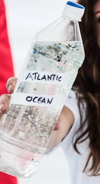 An assortment of microplastic fragments, filaments, and fibers from the North Atlantic Subtropical Gyre displayed in a disposable water bottle.