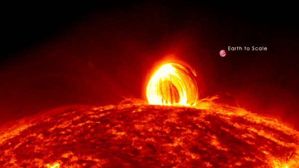 Coronal rain after a solar flare, shown with Earth to scale. The rain looks like a glowing, pouring loop coming out of the Sun. The Earth to Scale is less than one tenth the size of the loop.