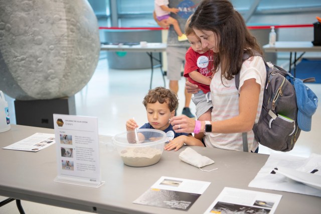 A women and her two children look interact with an exhibit in a science center.
