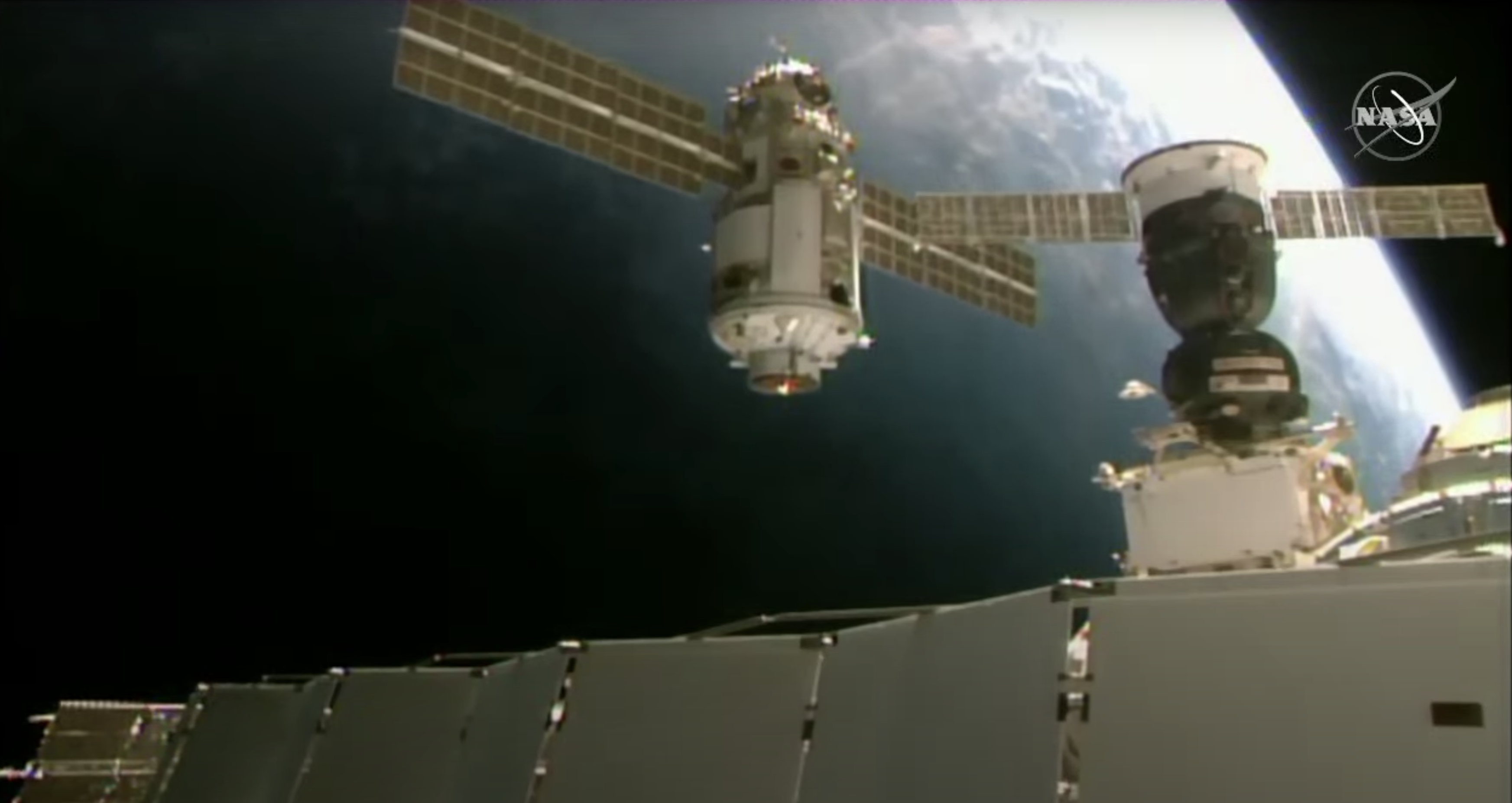 new module with solar panels flies near space station with Earth in background