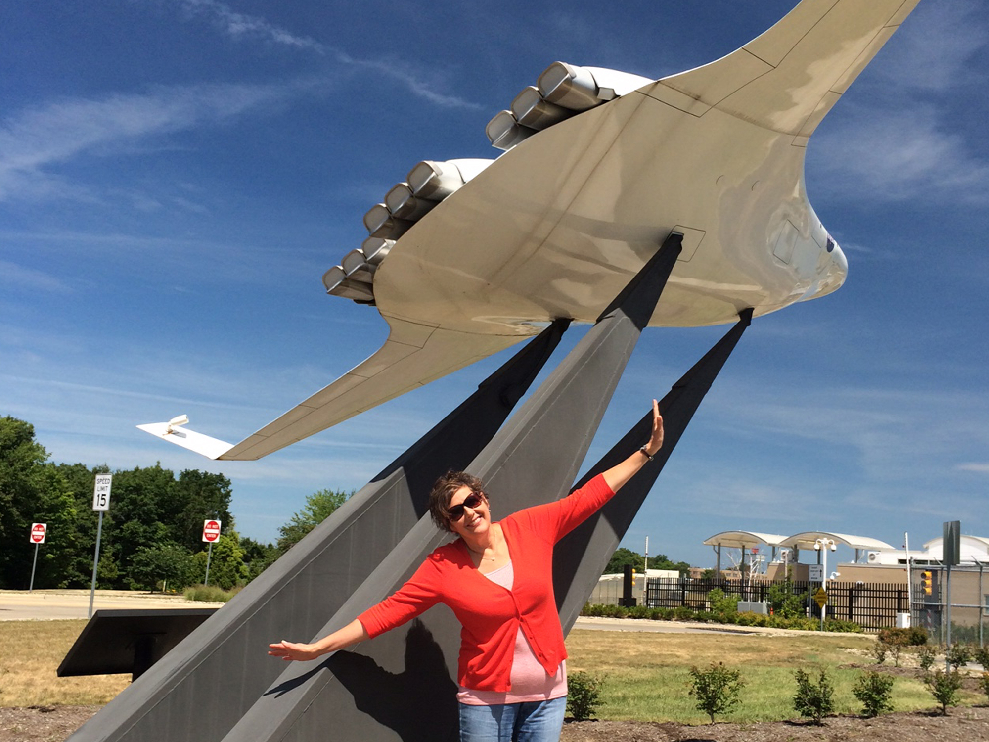 NASA employee near an airplane monument spreading her arms out, "Spread Your Wings".