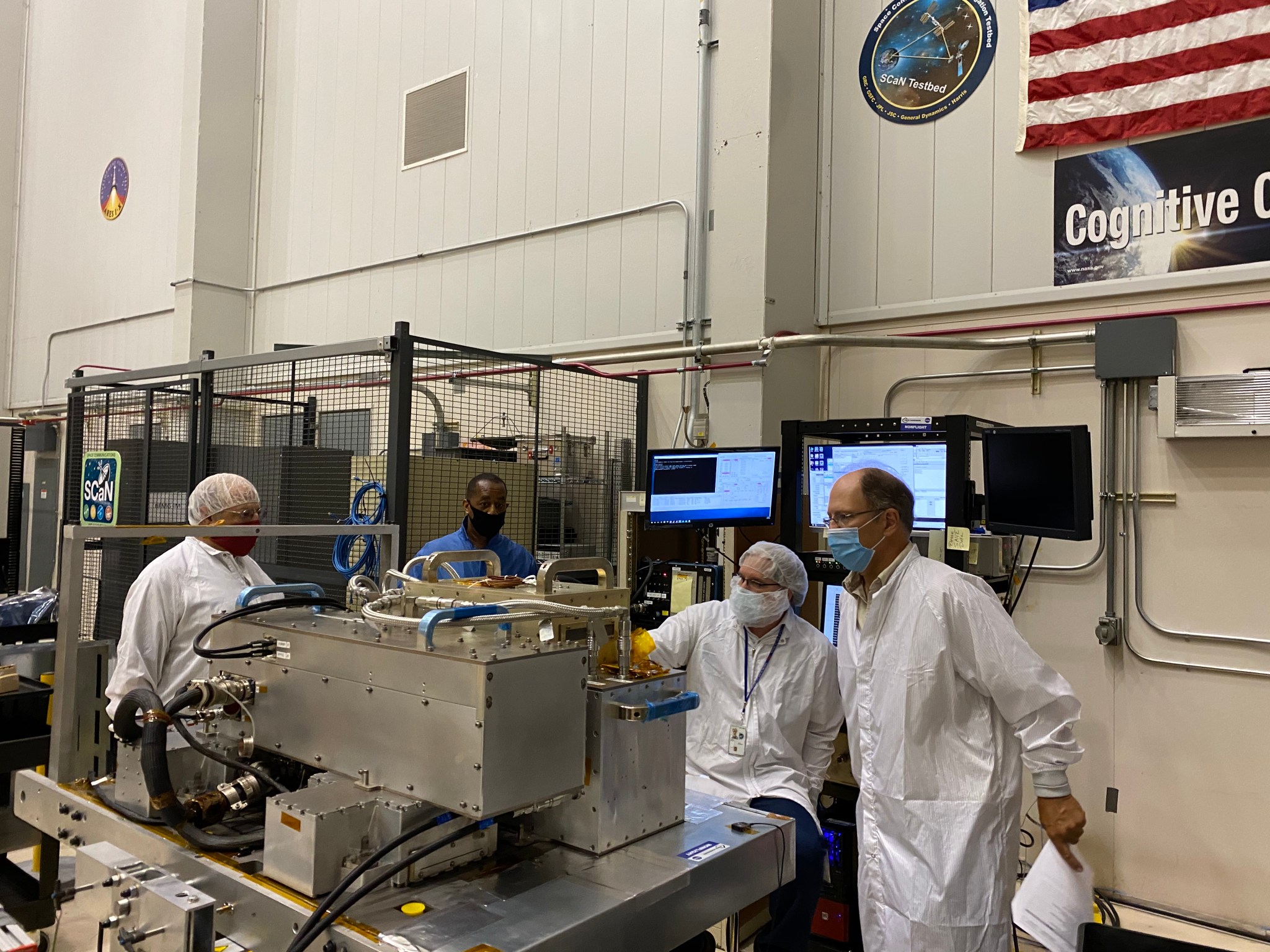 Researchers in a lab surround space hardware.