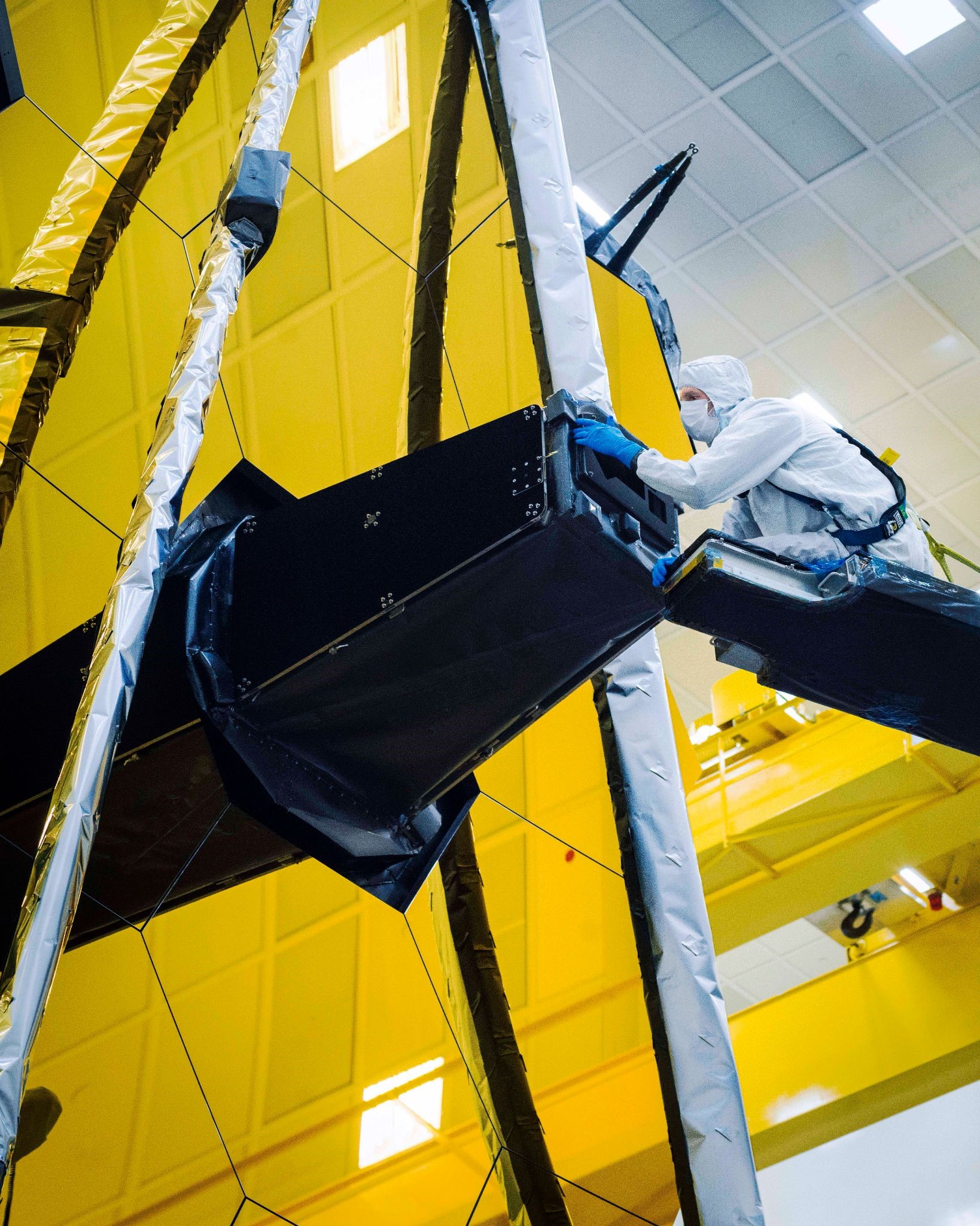 Ball Aerospace technician Larkin Carey can be seen carefully removing Webb’s "lens cap" from the Aft Optics Subsystem which has kept the observatory’s sensitive instruments clean, contaminant-free, and protected.