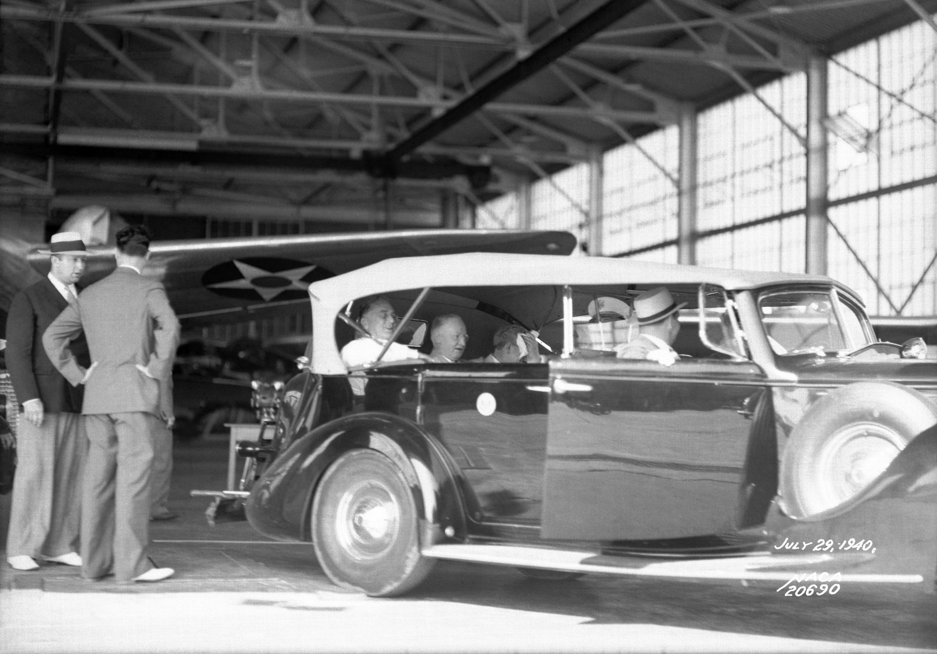 President Franklin D. Roosevelt, seen inside the car at far left, visits a hangar on July 29, 1940.