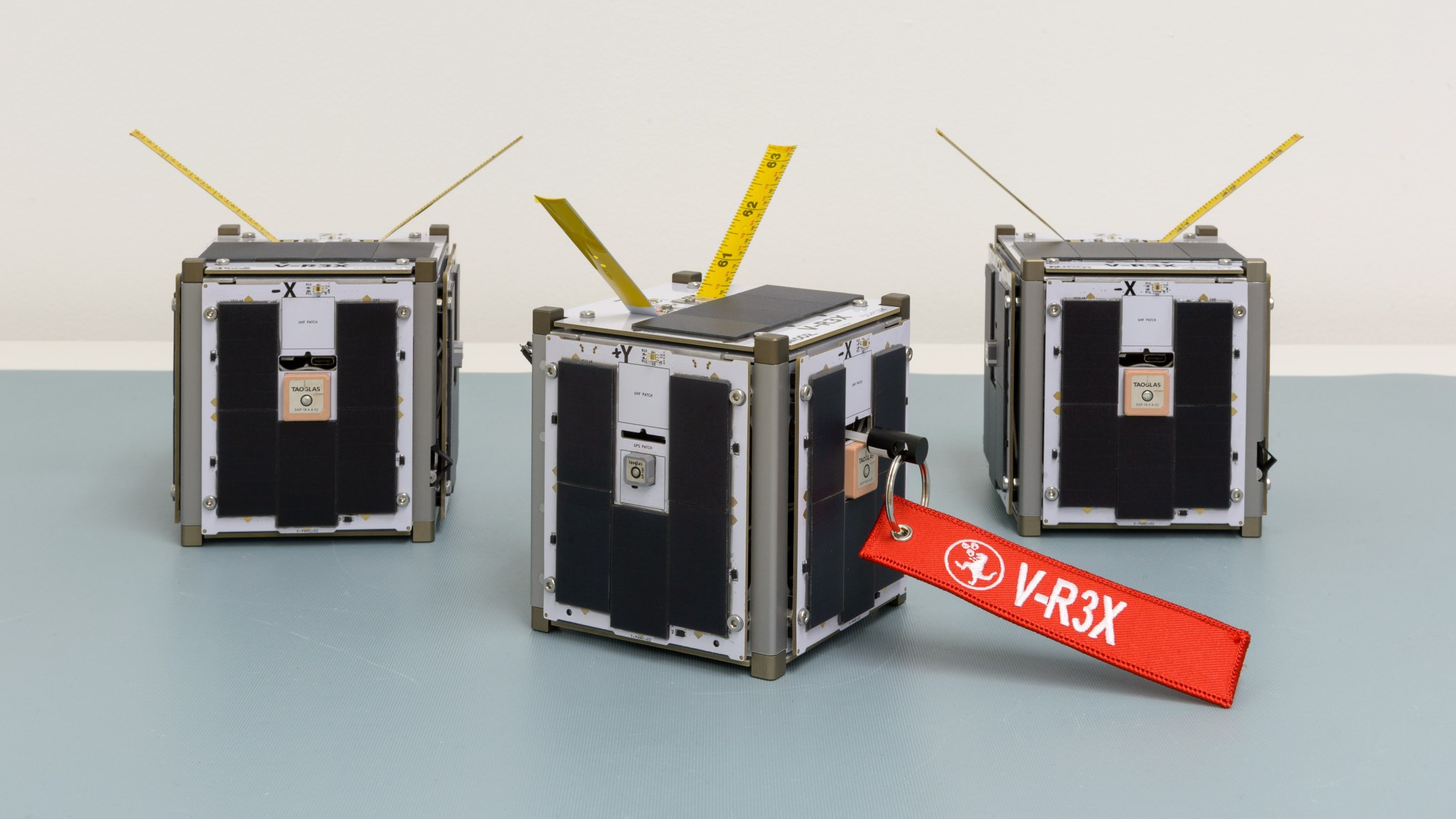Three small cube-shaped devices, one with a red tag that reads 'V-R3x'.