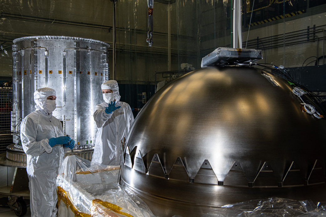 Engineers at NASA’s Goddard Space Flight Center in Greenbelt, MD, prepare for a propellant tank to be inserted into the cylinder in the background at left. The cylinder is one of two that make up Europa Clipper’s propulsion module.