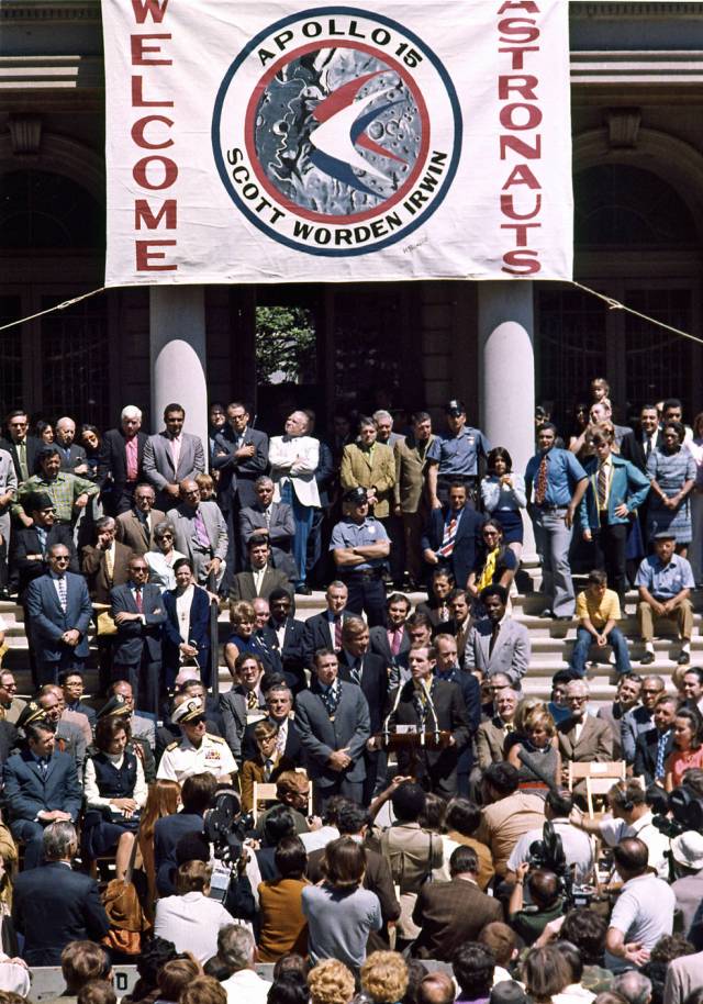 A crowd gathers to hear Apollo 15 astronauts with a Welcome Home banner hangs in the background