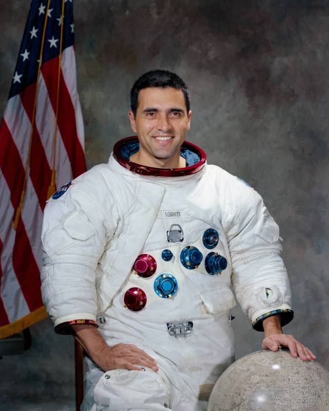 Harrison H. Schmitt posing in spacesuit in front of American flag